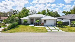 A modern two-story house with a garage, a well-maintained lawn, and a variety of plants. - Private Pool/Spa Home w/ Outdoor Kitchen, Near (Bonita Springs)