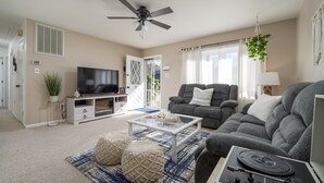 Ein Wohnzimmer mit einer Couch, einem Couchtisch, einem Fernseher und einem Deckenventilator.
