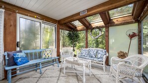 Eine überdachte Veranda mit Korbmöbeln, einer Bank und einem Tisch.