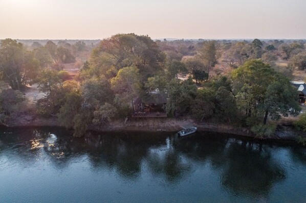 Vista aérea de una propiedad a orillas del río con un muelle y un bote pequeño.