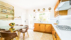 Een moderne keuken met een glazen eettafel, houten kastjes en uitzicht op de omgeving.