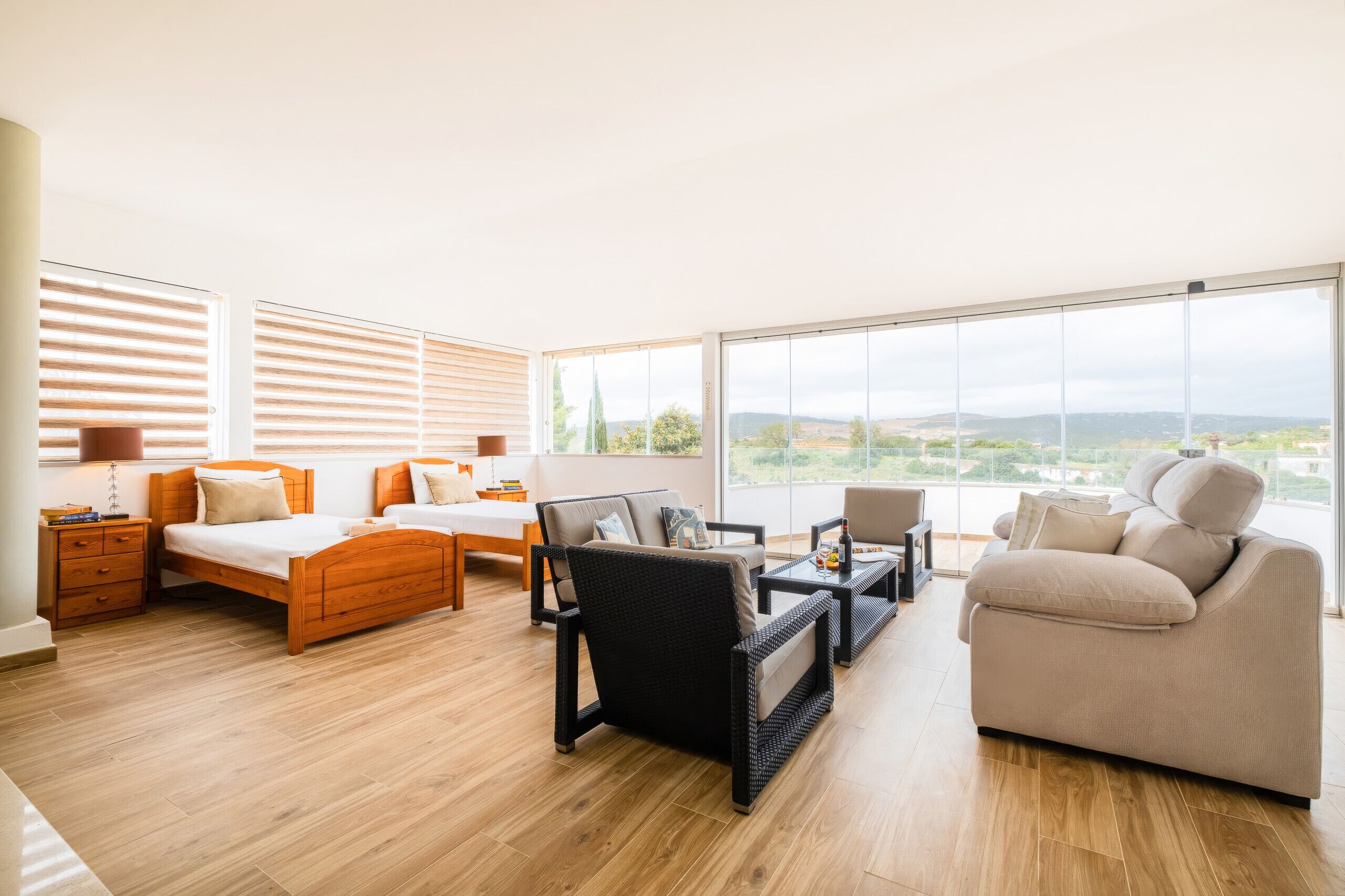 Un salón espacioso con un ventanal grande, un sofá, una mesa de centro y una cama con cabeceros de madera.