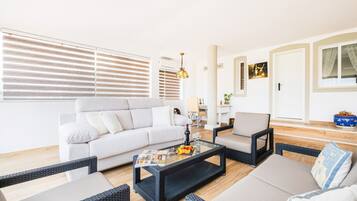 A modern living room with a sofa, two armchairs, a coffee table, and a dining table.