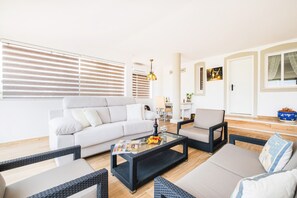 A modern living room with a sofa, two armchairs, a coffee table, and a dining table.