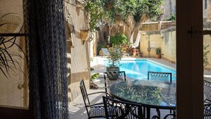 Un patio al aire libre con piscina, rodeado de muros de piedra y plantas en macetas.