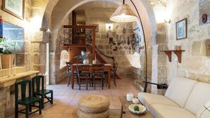 Un interior rústico con paredes de piedra, una mesa de comedor de madera y un sofá.