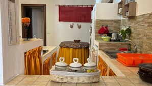 A modern kitchen with a stone backsplash, a built-in oven, and a sink. There is a small dining area with a table and chairs. - House in Silius R5130 (Silius)