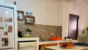 A modern kitchen with a central island, a built-in oven, a dishwasher, and a sink with a stone backsplash. - House in Silius R5130 (Silius)