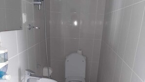 A small, compact bathroom with a white sink, toilet, and shower. - Kibar Apart Pansiyon (Kusadasi)