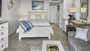 Une chambre d’hôtel comprenant un lit, un bureau, un canapé, une télévision et un coin cuisine.