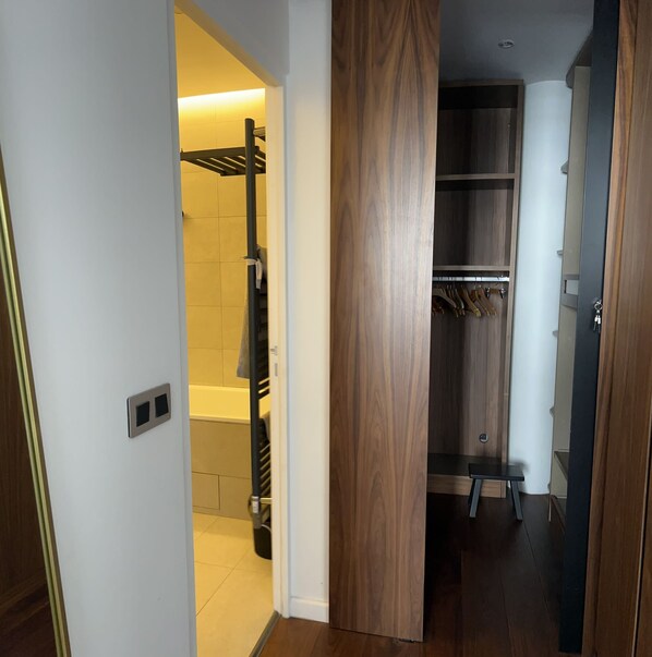 A hallway with a wooden wardrobe, a black metal rack, and a tiled shower area. - Appt River view next Eiffel Tour & Roland-Garros (Boulogne-Billancourt)