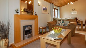 Una sala de estar acogedora con chimenea, techo de madera y un comedor con mesa y sillas.