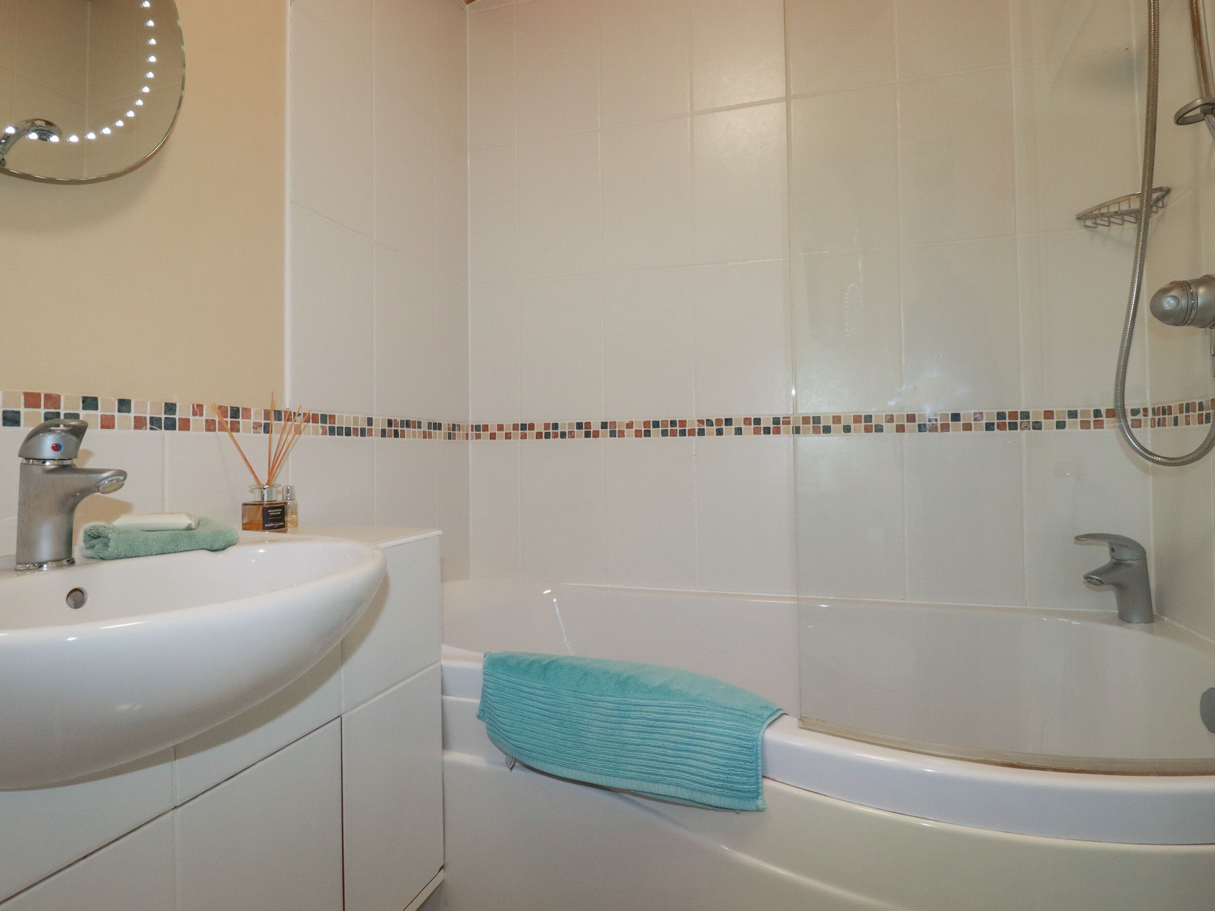 A bathroom with a sink, a mirror, a shower, and a bathtub.