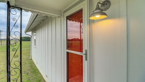 Une façade blanche, une porte en verre et un portail en métal.
