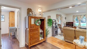 Un salon avec un meuble en bois, un canapé, une télévision et une plante décorative.