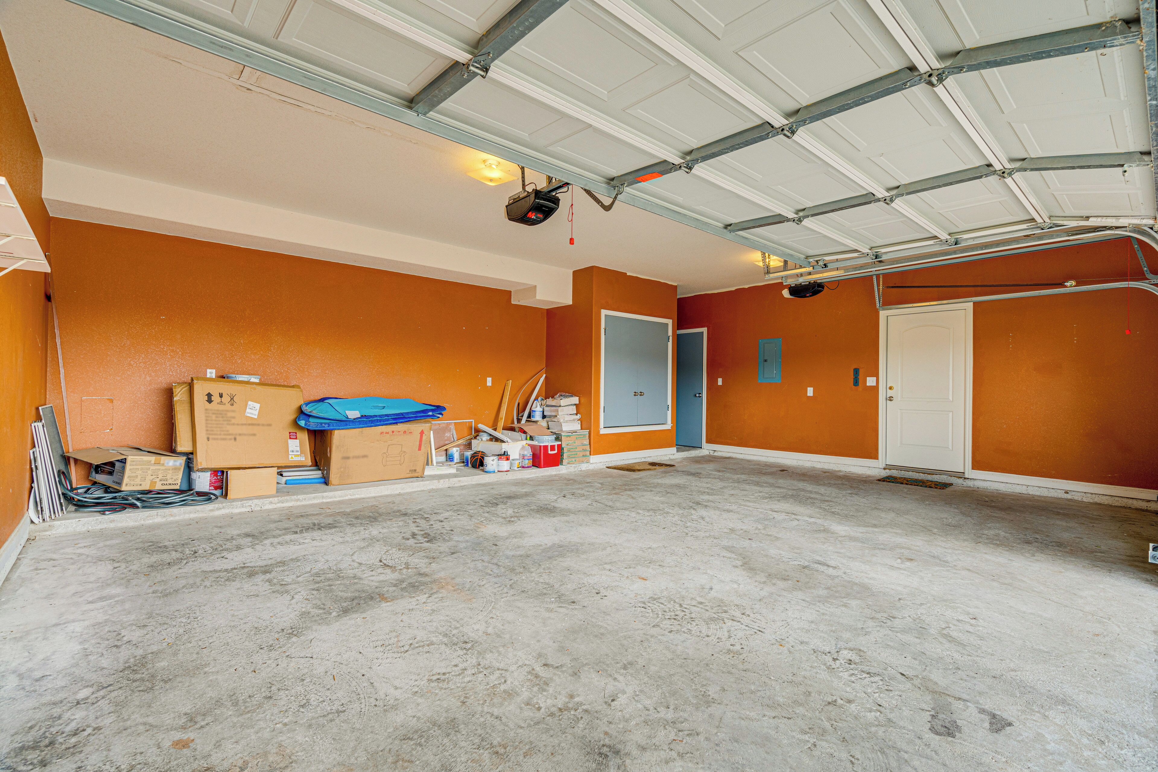 A spacious garage with orange walls, a concrete floor, and a metal roof.