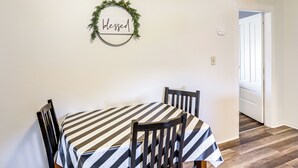 A dining area with a table covered by a striped tablecloth, two wooden chairs, and a wall-mounted sign that reads "blessed". - Greenwich Countryside Apartment w/ Shared Yard (Greenwich)