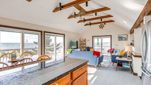 A spacious kitchen with a large island, wooden cabinets, and a view of the ocean. - Eastham Beach House w/ Bay Views & Beach Access! (Eastham)