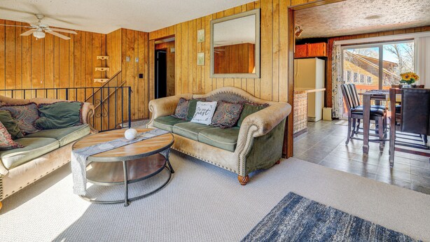 A cozy living room with a green sofa, a coffee table, and a staircase leading to another room. - Charming Elk Mountain Home: Hunt, Hike & Fish! (Elk Mountain)