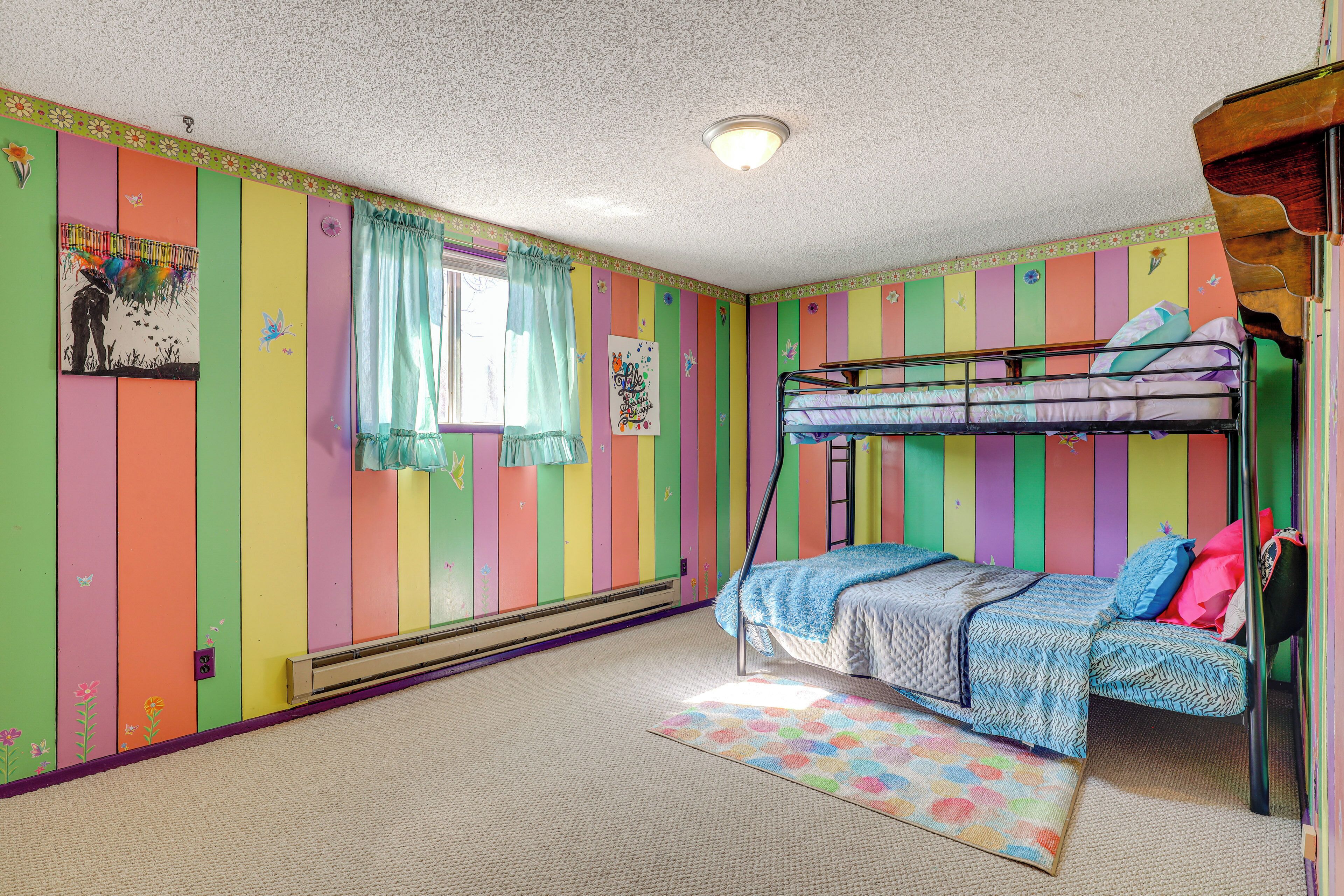 A colorful room with a bunk bed, striped walls, and a window with curtains.