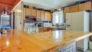 A kitchen with wooden cabinets, a large wooden countertop, a microwave, a refrigerator, and a sink. - Charming Elk Mountain Home: Hunt, Hike & Fish! (Elk Mountain)