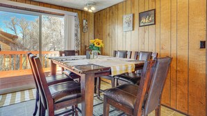 A wooden-paneled room with a dining table, chairs, and a view through large windows. - Charming Elk Mountain Home: Hunt, Hike & Fish! (Elk Mountain)