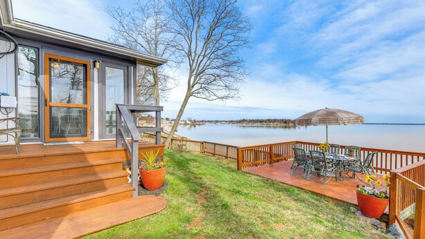 A deck with outdoor furniture, a wooden staircase, and a view of a lake. - Riverfront Colonial Beach Home w/ Private Beach! (Colonial Beach)