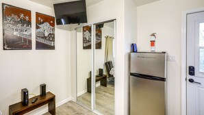 Una cocina compacta con refrigerador, un banco con control remoto y obras de arte en la pared.