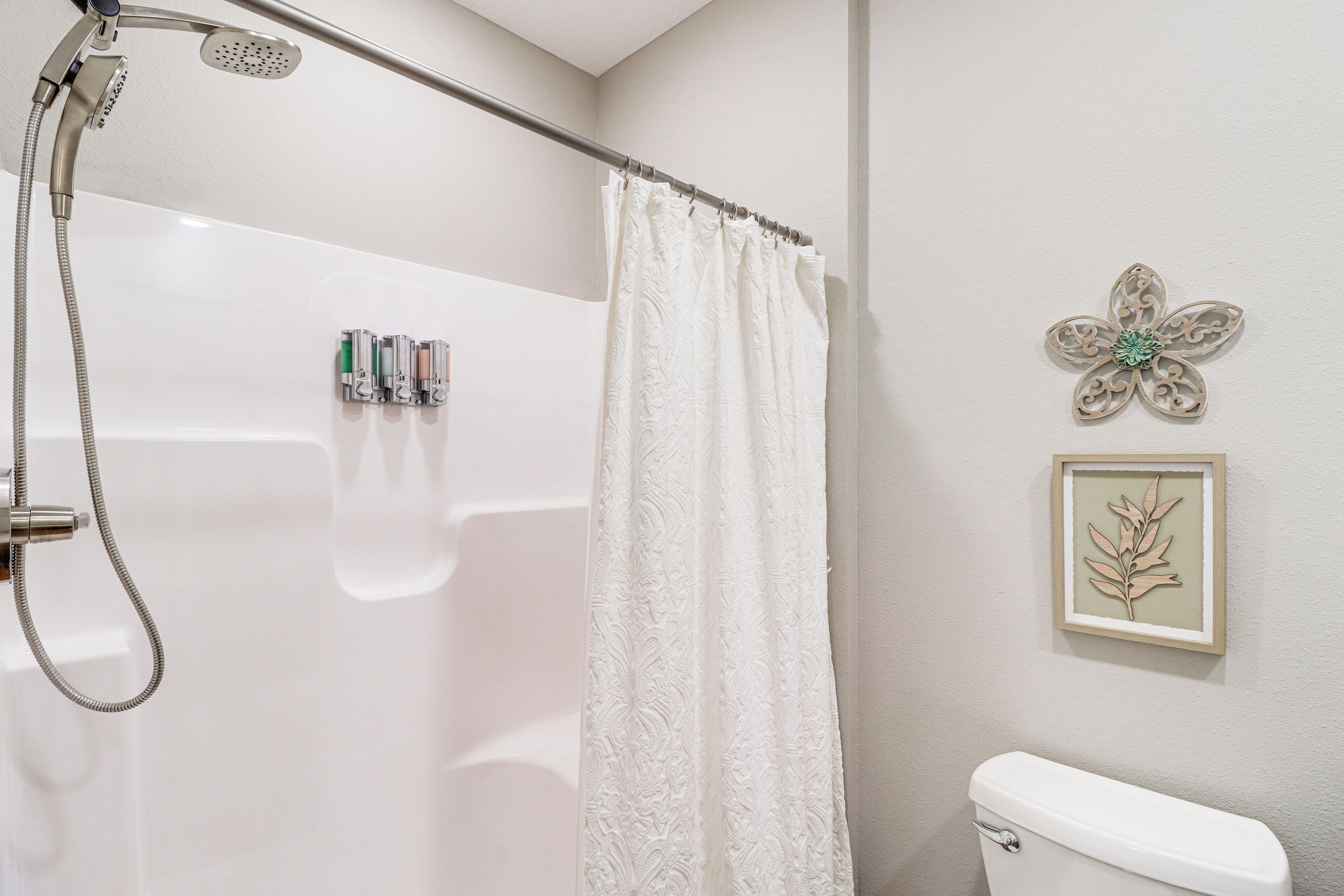 A bathroom with a shower, toilet, and a framed wall decoration.
