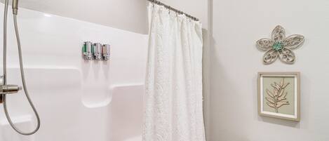 A bathroom with a shower, toilet, and a framed wall decoration.