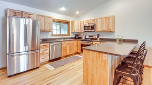 A modern kitchen with wooden cabinets, stainless steel appliances, and a central island with bar stools.