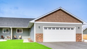 A two-story house with a garage, a well-maintained lawn, and a patio with chairs.