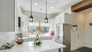 A modern kitchen with white cabinets, a large island, stainless steel appliances, and pendant lighting. - Dtwn Blowing Rock Condo w/ Private Hot Tub! (Blowing Rock)