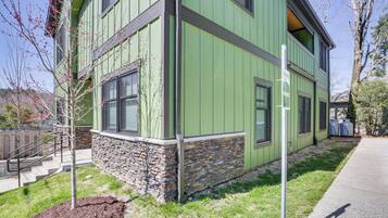 A two-story building with a stone foundation and green siding.