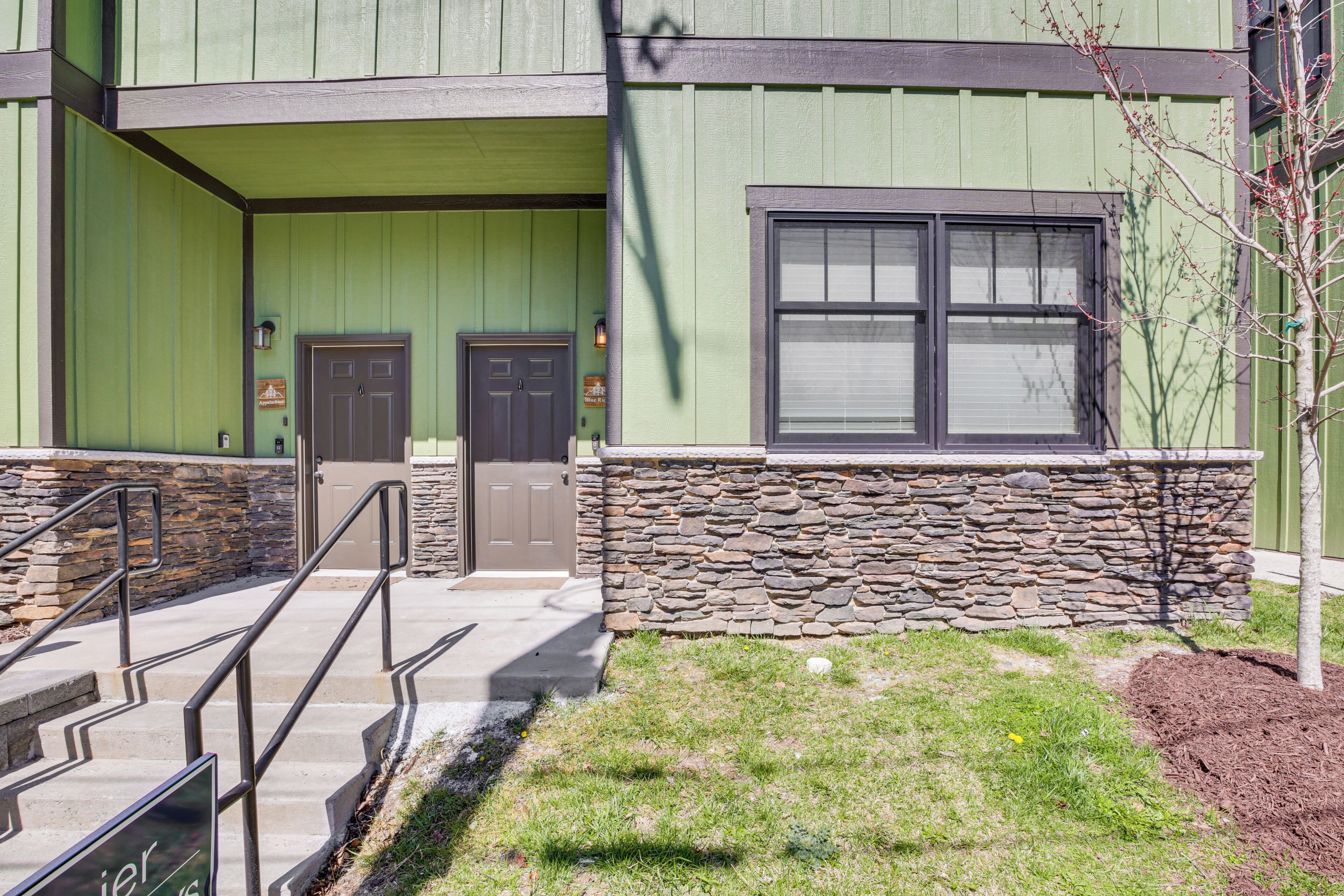A building with a green facade, a stone base, and a window with blinds.