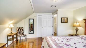 A bedroom with a bed, a zebra-patterned chair, a white door, and a lamp on a bedside table.