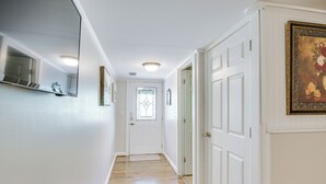 A hallway with white walls, wooden flooring, and white doors.