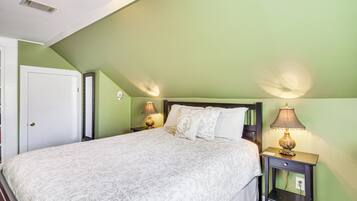 A bedroom with a bed, two bedside lamps, a nightstand, and a door.