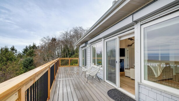A wooden deck with a glass door leading to a room with a view. - Lovely Rockaway Beach Home w/ Pacific Ocean Views! (Rockaway Beach)