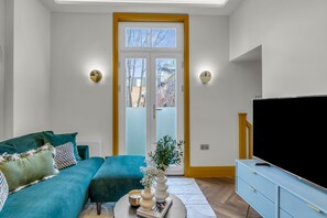 Un salon moderne avec un canapé de couleur turquoise, un téléviseur à écran plat et un meuble en bois.