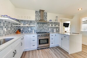 A modern kitchen with white cabinets, a stainless steel stove, and patterned backsplash tiles. - New Bern House w/ Gas Grill Near Neuse River! (New Bern)