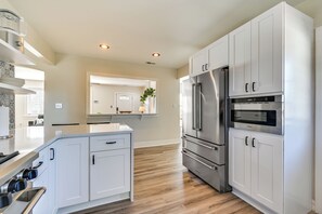 A modern kitchen with white cabinetry, stainless steel appliances, and a central island. - New Bern House w/ Gas Grill Near Neuse River! (New Bern)