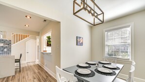 A dining area with a table set for four, white chairs, and a modern chandelier. - New Bern House w/ Gas Grill Near Neuse River! (New Bern)