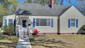 A single-story house with a front porch, a chimney, and a small front yard with a bush and a tree. - New Bern House w/ Gas Grill Near Neuse River! (New Bern)