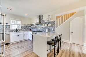 A modern kitchen with white cabinets, a marble island, and a patterned backsplash. - New Bern House w/ Gas Grill Near Neuse River! (New Bern)