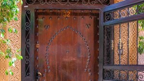 A large wooden door with the number 32, a metal gate, and a decorative wall with intricate patterns.