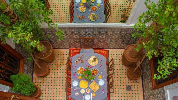 A dining area with a table set for a meal, surrounded by potted plants and traditional decor.