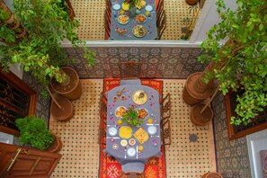 A dining area with a table set for a meal, surrounded by potted plants and traditional decor. - Riad Amely (Marrakech)
