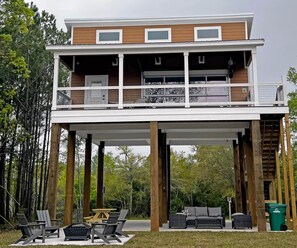 A two-story house with a balcony, outdoor seating, and a garage. - The Clermont at Clermont Bay (Hancock County)