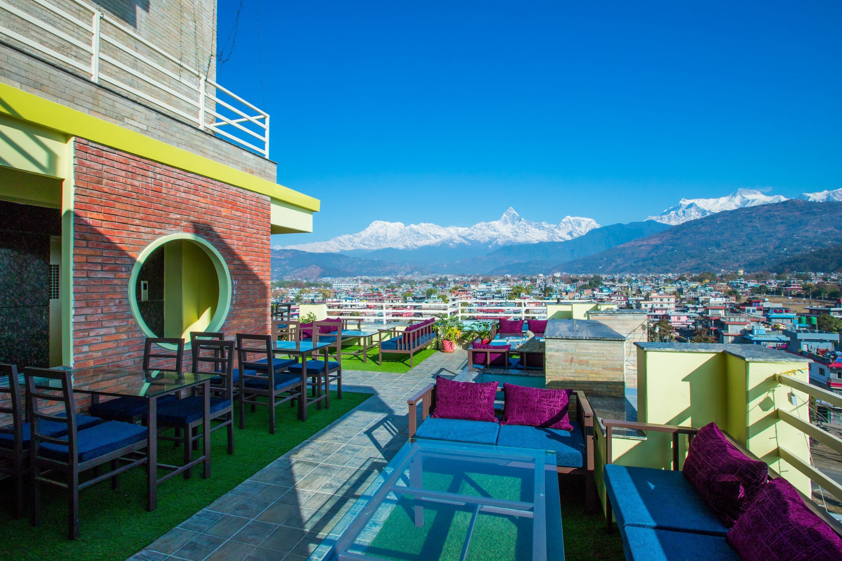 An outdoor terrace with seating and a view of snow-capped mountains.